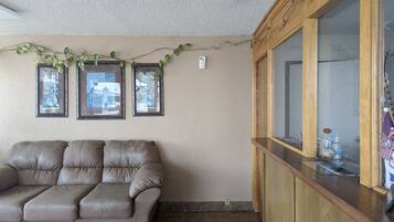 A living room with a brown leather sofa, three framed pictures on the wall, and a wooden cabinet with a mirror.