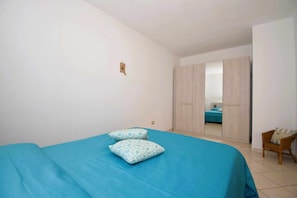 A bedroom with a bed, two pillows, a wardrobe, and a chair.