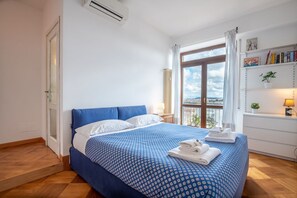 A bedroom with a bed, a window, a radiator, a shelf with books, and a plant. - Matilde's view apartment Saint Peter (roma)