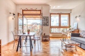 A spacious living area with a dining table, chairs, a sofa, and a coffee table. Large windows provide a view of the cityscape. - Matilde's view apartment Saint Peter (roma)