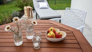A wooden table with glass vases, a bowl of apples, and a candle.