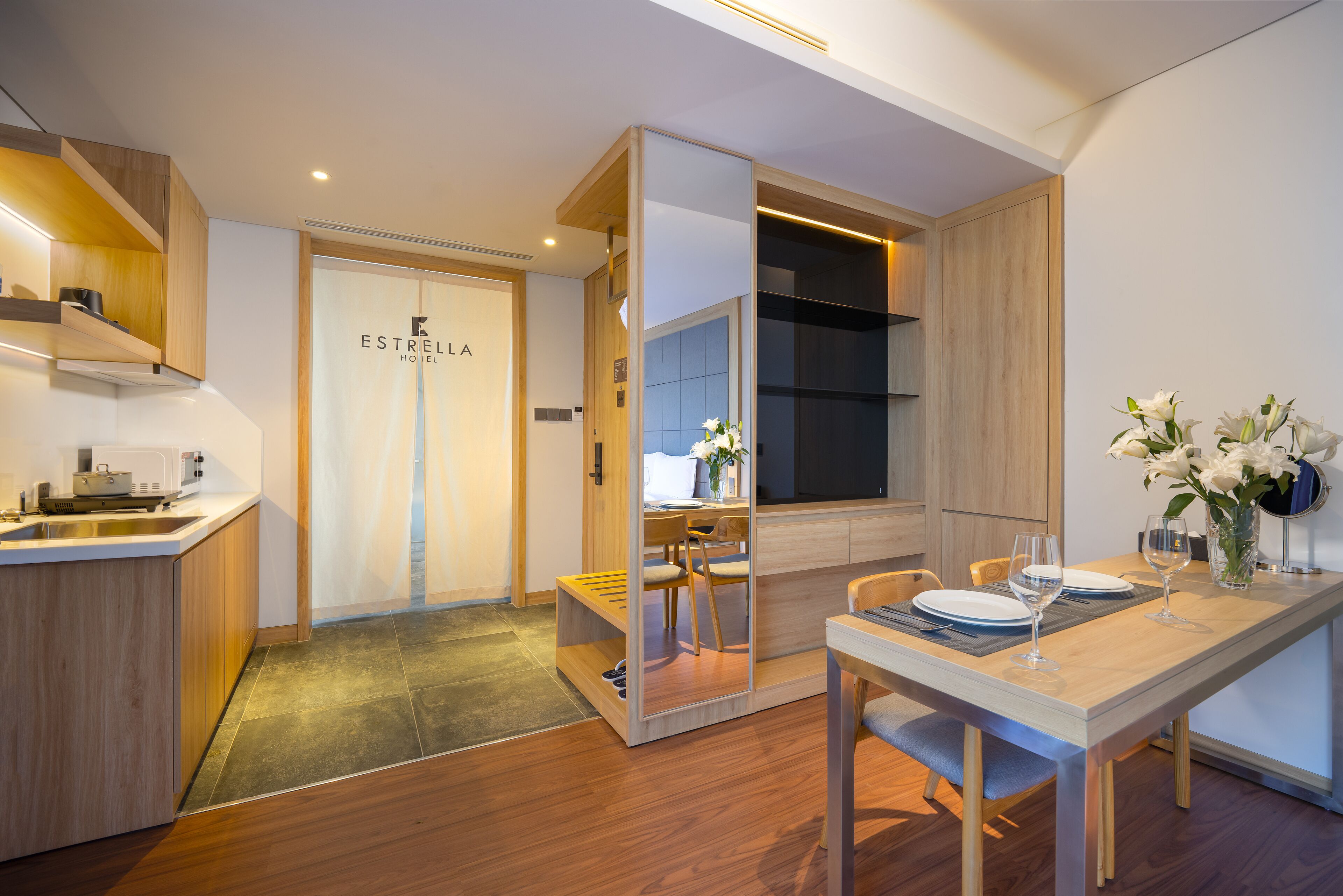 A modern kitchen with wooden cabinets, a built-in stove, and a dining area with a table set for two.