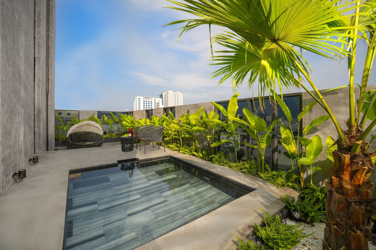 A rooftop pool with a modern design, surrounded by lush greenery and a cityscape view.