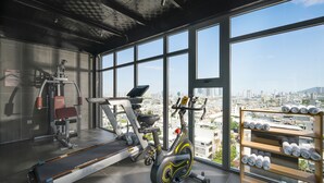 A gym with exercise equipment, a treadmill, an elliptical, and a rack of towels. - Estrella Boutique Hotel (Da Nang)