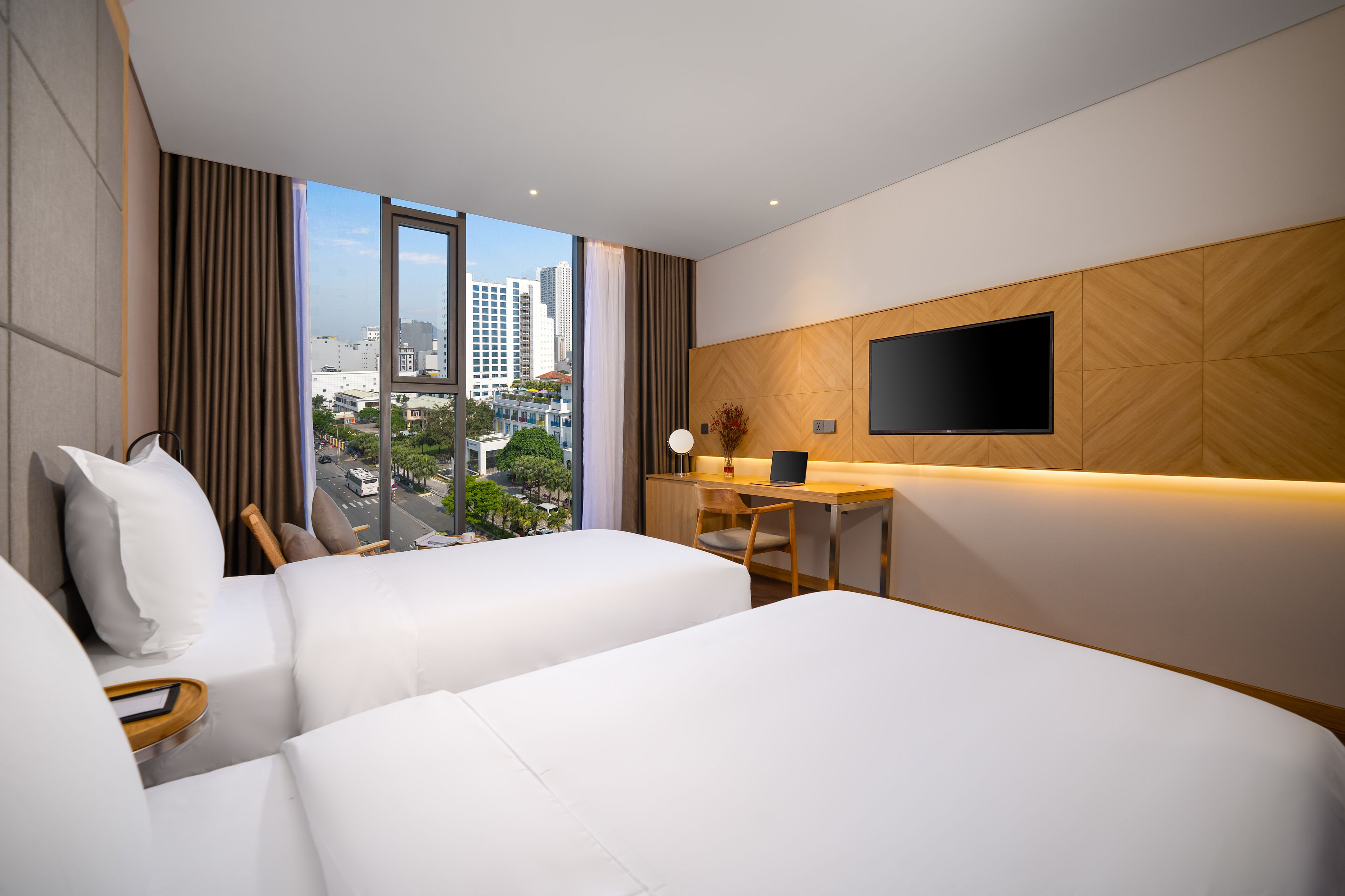 Une chambre d’hôtel avec deux lits, un bureau, une télévision et une vue sur la ville.