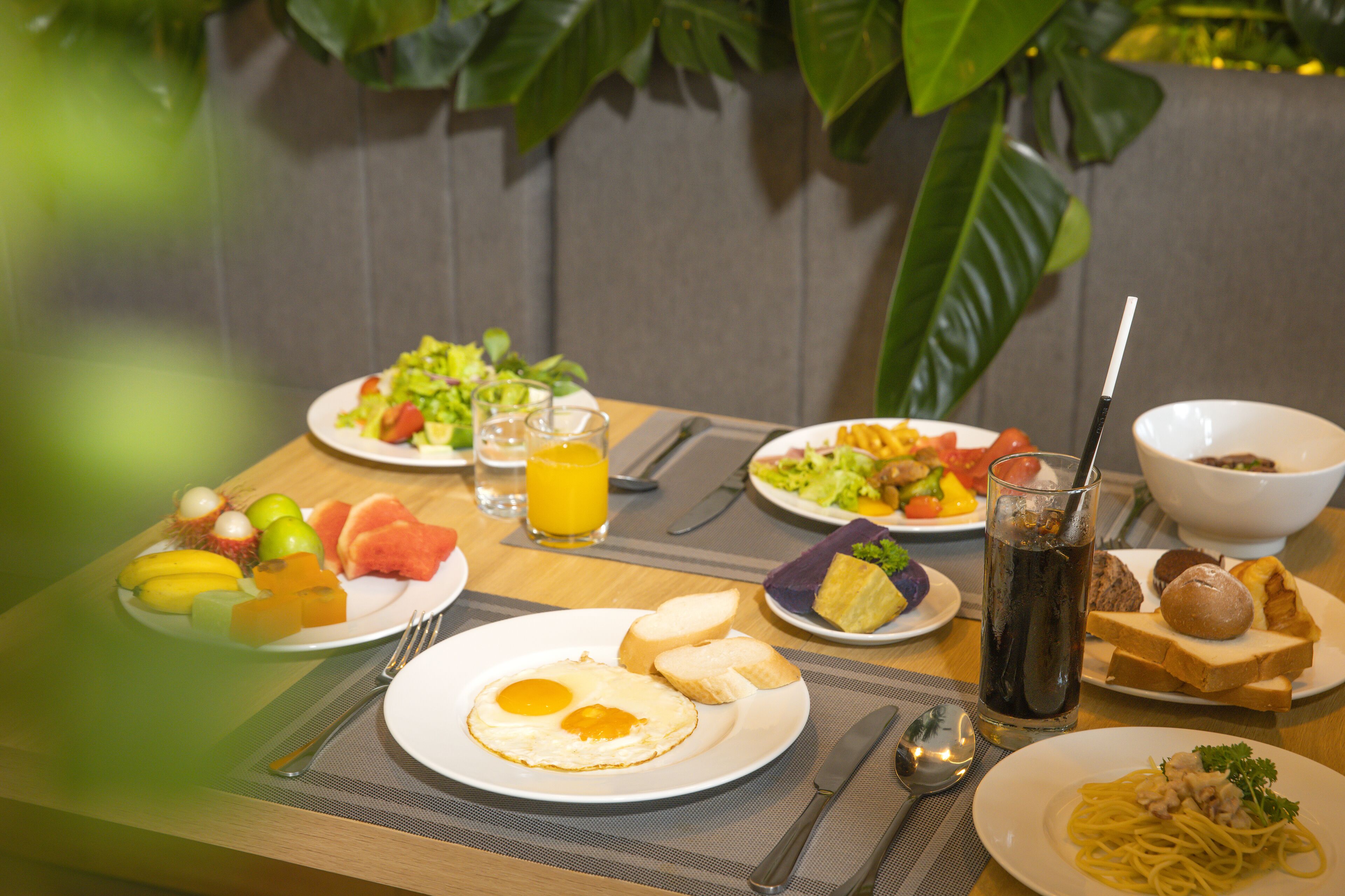 A breakfast table with plates of eggs, toast, fruit, and a glass of orange juice.