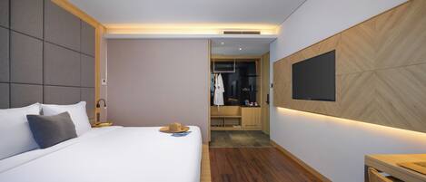 Ein modernes Hotelzimmer mit einem großen Bett, einem Holztisch und einem an der Wand befestigten Fernseher.