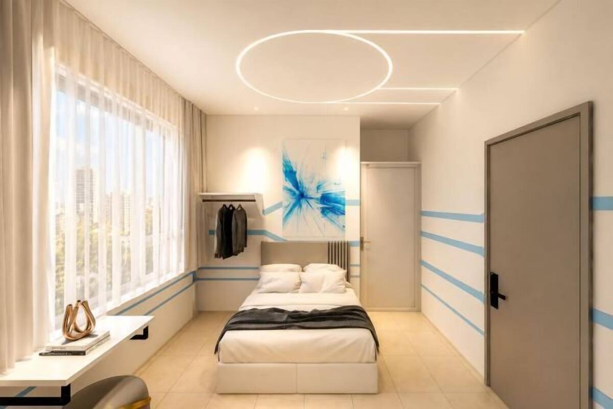 A modern bedroom with a bed, a desk, and a city view.
