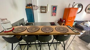 A dining table with four placemats, a water dispenser, and a cabinet with bottles. - The funny Tuna in Zahara de los Atunes (Zahara de los Atunes)