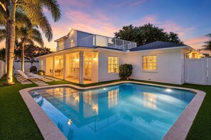 A two-story house with a swimming pool, a covered patio, and a fenced backyard.