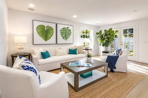 A modern living room with a sofa, coffee table, and a large plant. - Santa Lucia I By Hotel Home Stays (West Palm Beach)