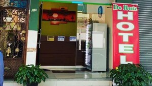 The exterior of De Ruiz Hotel with a green signboard, a glass entrance, and a red signboard. - D Ruiz Hotel (Quevedo)