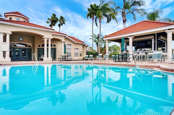 A swimming pool with lounge chairs and palm trees in the background.