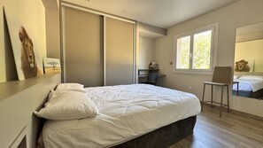 Un dormitorio con una cama grande, un escritorio y una silla. Hay una ventana con vistas a árboles y un cuadro de un león en la pared.