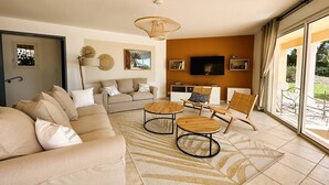 Una sala de estar moderna con un sofá, dos sillones, una mesa de centro y un televisor.