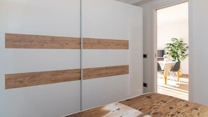 A room with a wooden floor, a white door, and a view of a dining area with chairs and a table. - APPARTAMENTO VICINO AL MARE - VICINO AL MARE (Portoferraio)