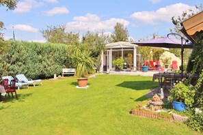 Relax in a serene outdoor space with lounge chairs, a dining table, and lush greenery.