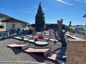 Explore the resort's outdoor recreational area featuring play structures, pathways, and a natural setting with a large tree and a building.