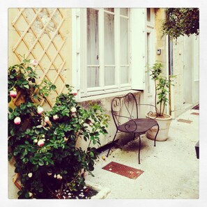 A courtyard with a wrought iron chair, a potted plant, and a lattice wall. - Spacious, light & airy, Romantic village home set off Monflanquin Village Square (Monflanquin)