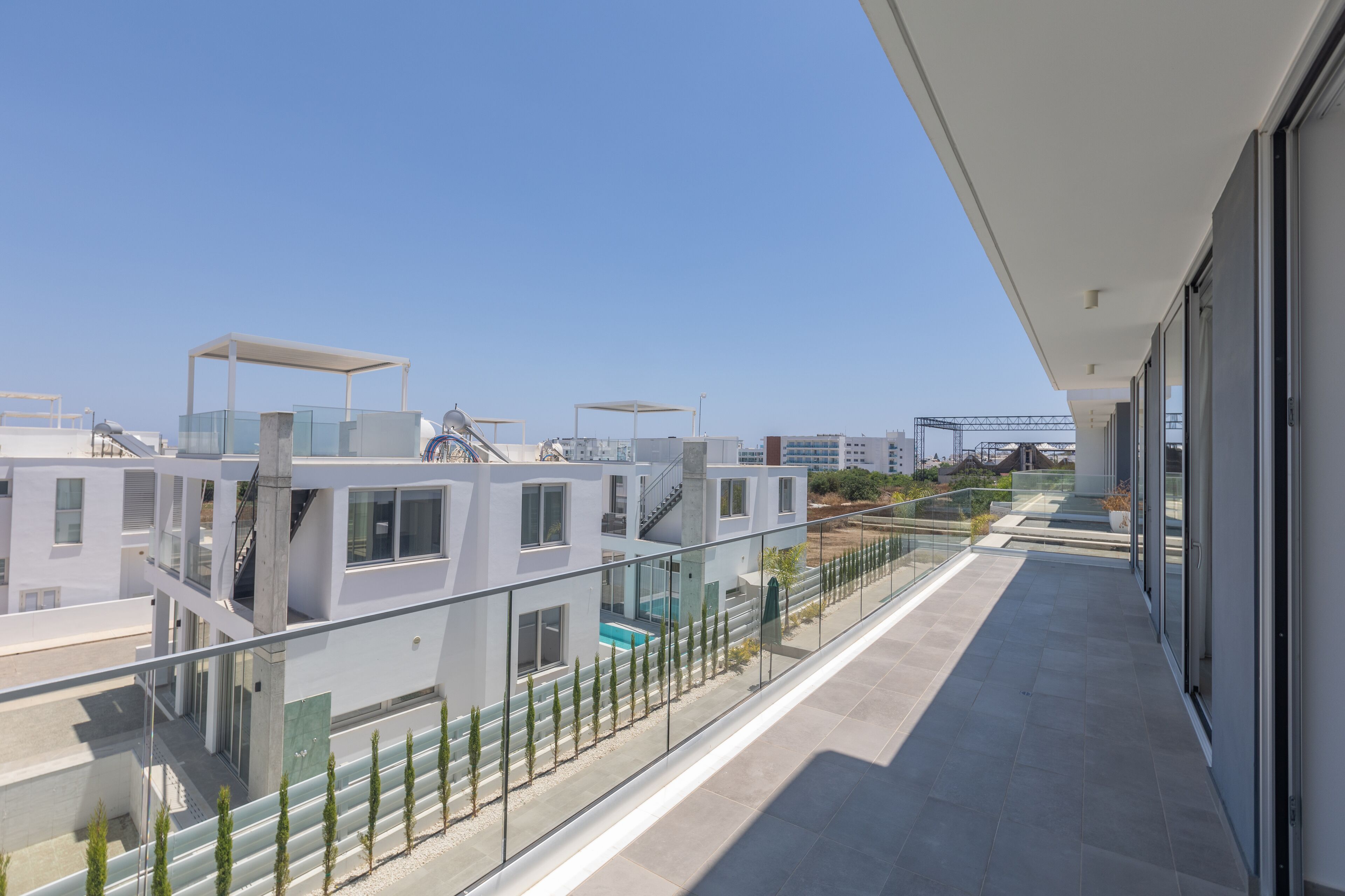 Ein modernes Gebäude mit Glasbalkon, Pool und freiem Blick auf die Umgebung.