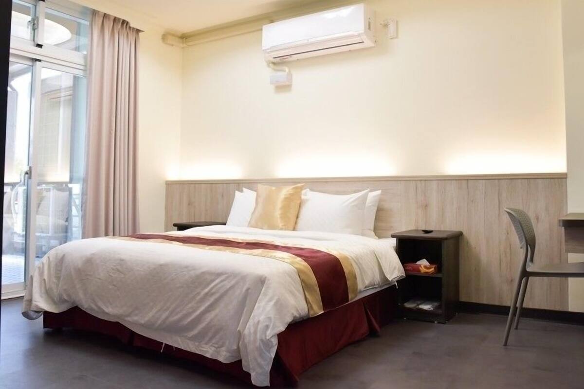 A hotel room with a bed, a desk, and a chair.