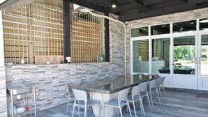 An outdoor bar area with a stone countertop, white chairs, and a stone wall with a grid pattern. - LONG LIFE B&B (Taitung)