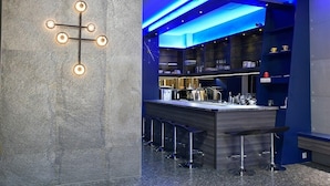 A modern kitchen with a bar area, granite countertops, and blue lighting accents. - LONG LIFE B&B (Taitung)