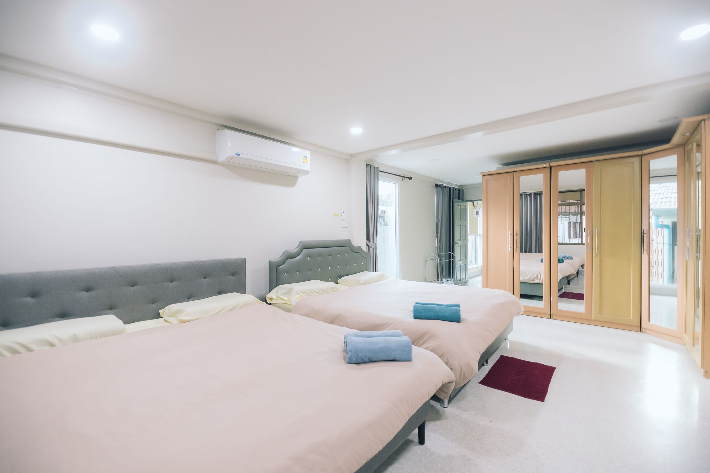 A modern hotel room with two beds, a wardrobe, and a window with curtains.