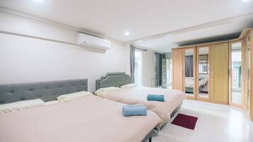 A modern hotel room with two beds, a wardrobe, and a window with curtains.