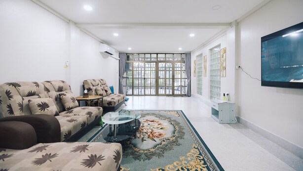 A modern living room with a sofa, a coffee table, and a TV mounted on the wall. - Paradise Found 4BR Villa,Fits 22 PAX, 6-Min to Lee Garden (Hat Yai)