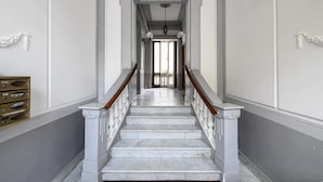 A grand staircase with marble steps and wooden railings leading to a doorway.