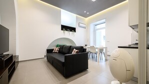 A modern living room with a black sofa, a flat-screen TV, and a unique egg-shaped chair.