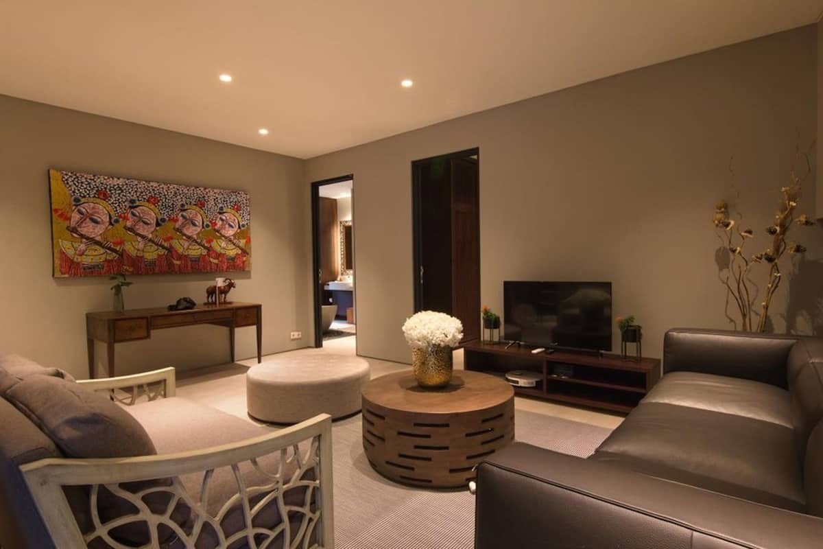 A modern living room with a sofa, a round coffee table, a TV, and a painting on the wall.