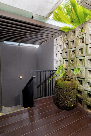 A staircase with a metal railing, a wall with square cutouts, and a moss-covered planter with a plant. - The Ning Resort Ubud (Ubud)