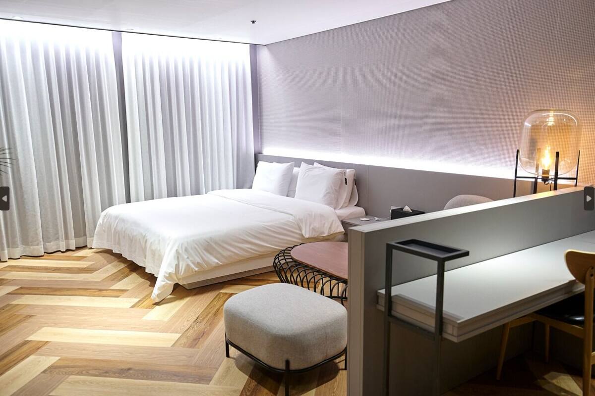 A modern hotel room with a large bed, a desk, and a chair.