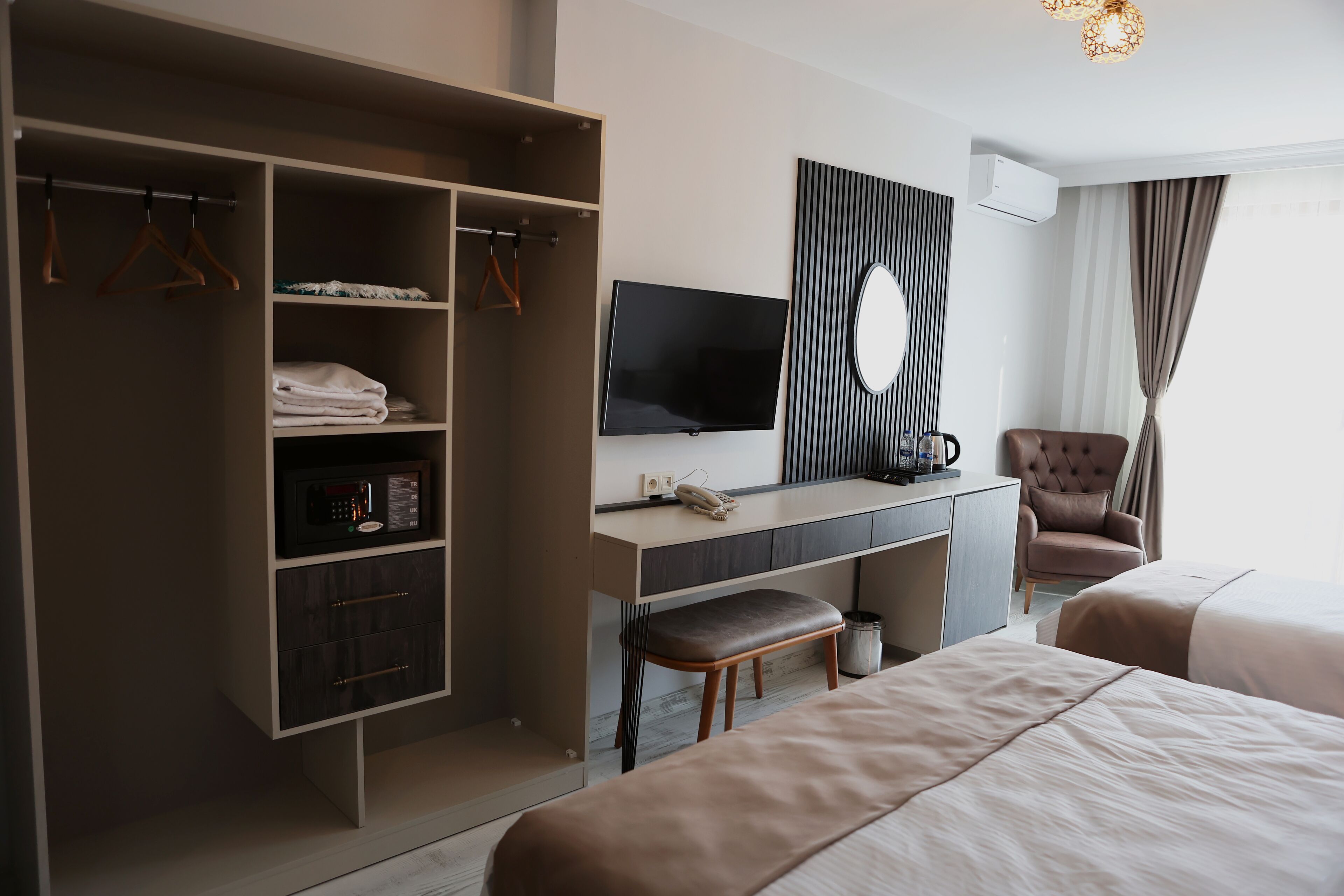 A hotel room with a bed, a desk with a TV, a wardrobe, and a chair.