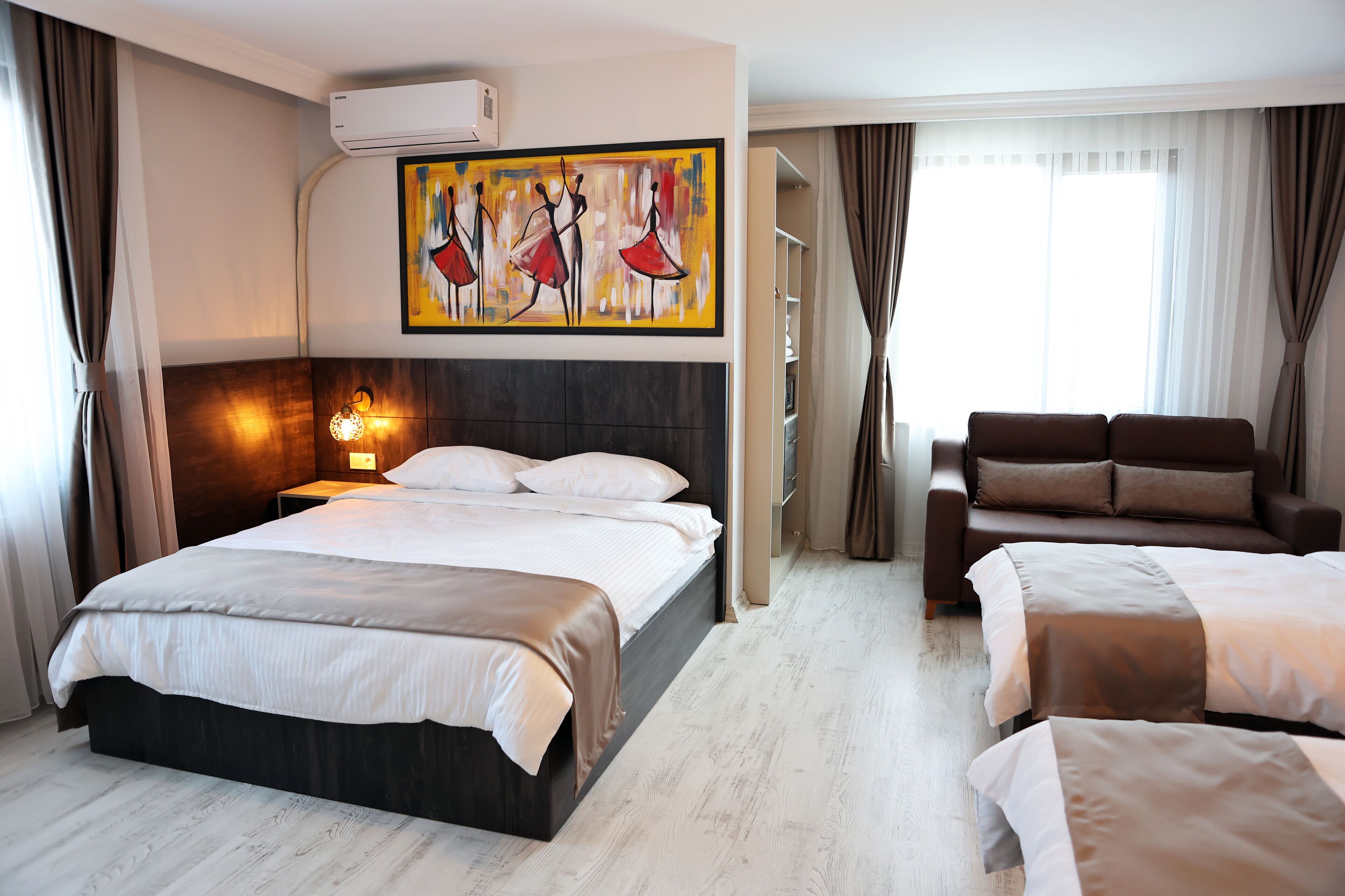 A hotel room with a large bed, a sofa, and a painting on the wall.