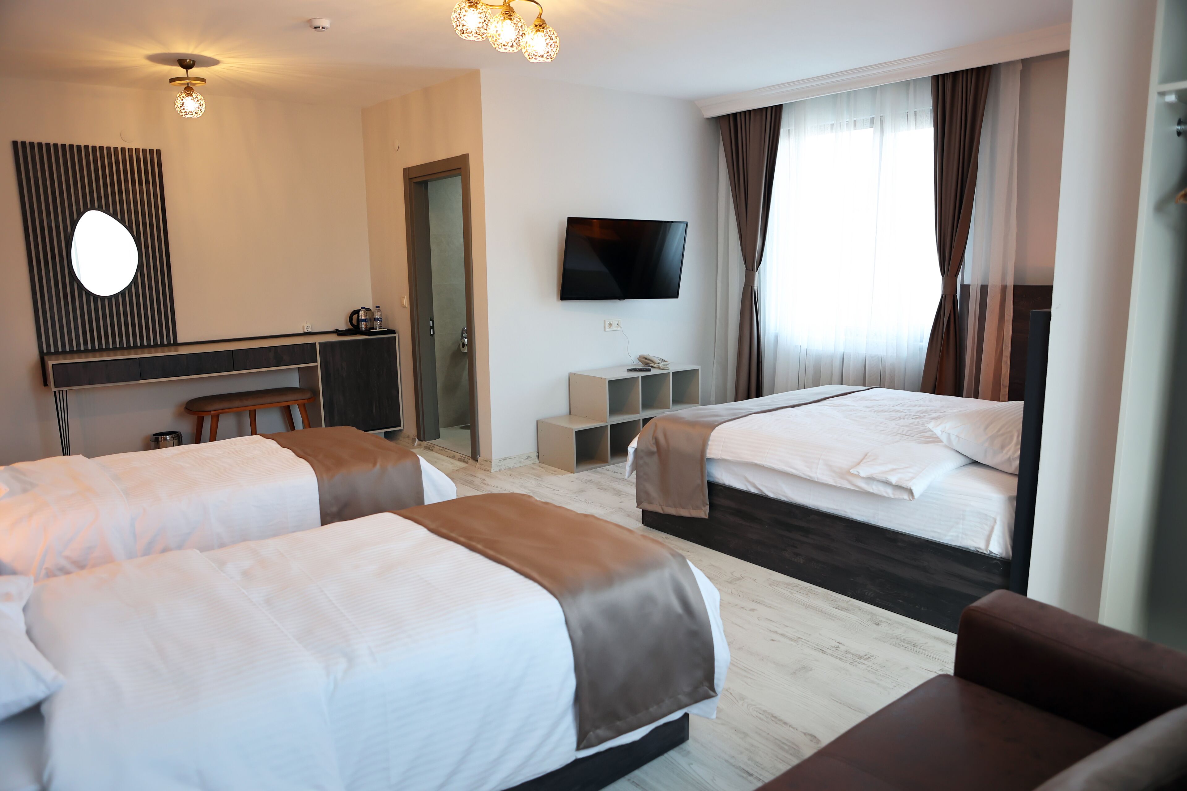 A hotel room with two beds, a desk, a TV, and a seating area.