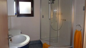 Une salle de bain avec une douche à parois de verre, un lavabo et un miroir.