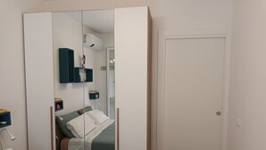 Une chambre à coucher avec un lit, une table de chevet, un miroir et une armoire.