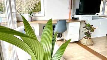 Une cuisine moderne dotée d’un téléviseur à écran plat, de meubles en bois et d’un coin repas comprenant une chaise et une table.