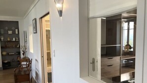 A hallway with a wooden floor, a dining area with a table and chairs, and a room with a large window and a view of the outdoors. - Sumptuous Beau-Rivage apartment with lake view and private beach (Annecy)