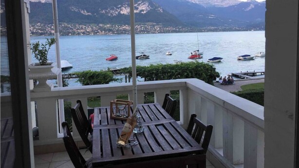 A balcony with a table and chairs, overlooking a lake with boats and mountains in the background. - Sumptuous Beau-Rivage apartment with lake view and private beach (Annecy)
