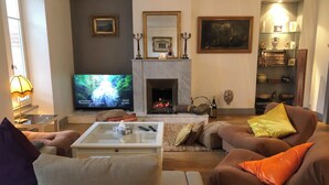 A living room with a television, fireplace, and various decorative items. - Sumptuous Beau-Rivage apartment with lake view and private beach (Annecy)