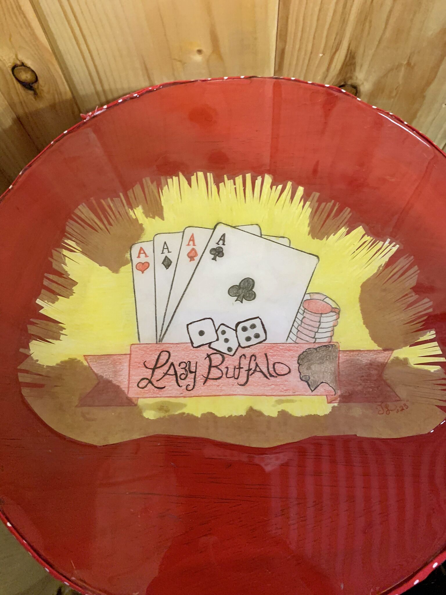 Une table rouge ornée du logo « Lazy Buffalo » et sur laquelle sont posées des jeux de cartes.