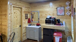 Une cuisine de taille réduite avec des murs en bois, un évier, un four à micro-ondes, un réfrigérateur et une poubelle.