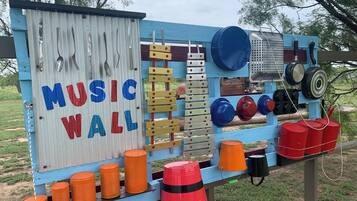 A blue and white structure labeled "MUSIC WALL" with various musical instruments and storage bins.