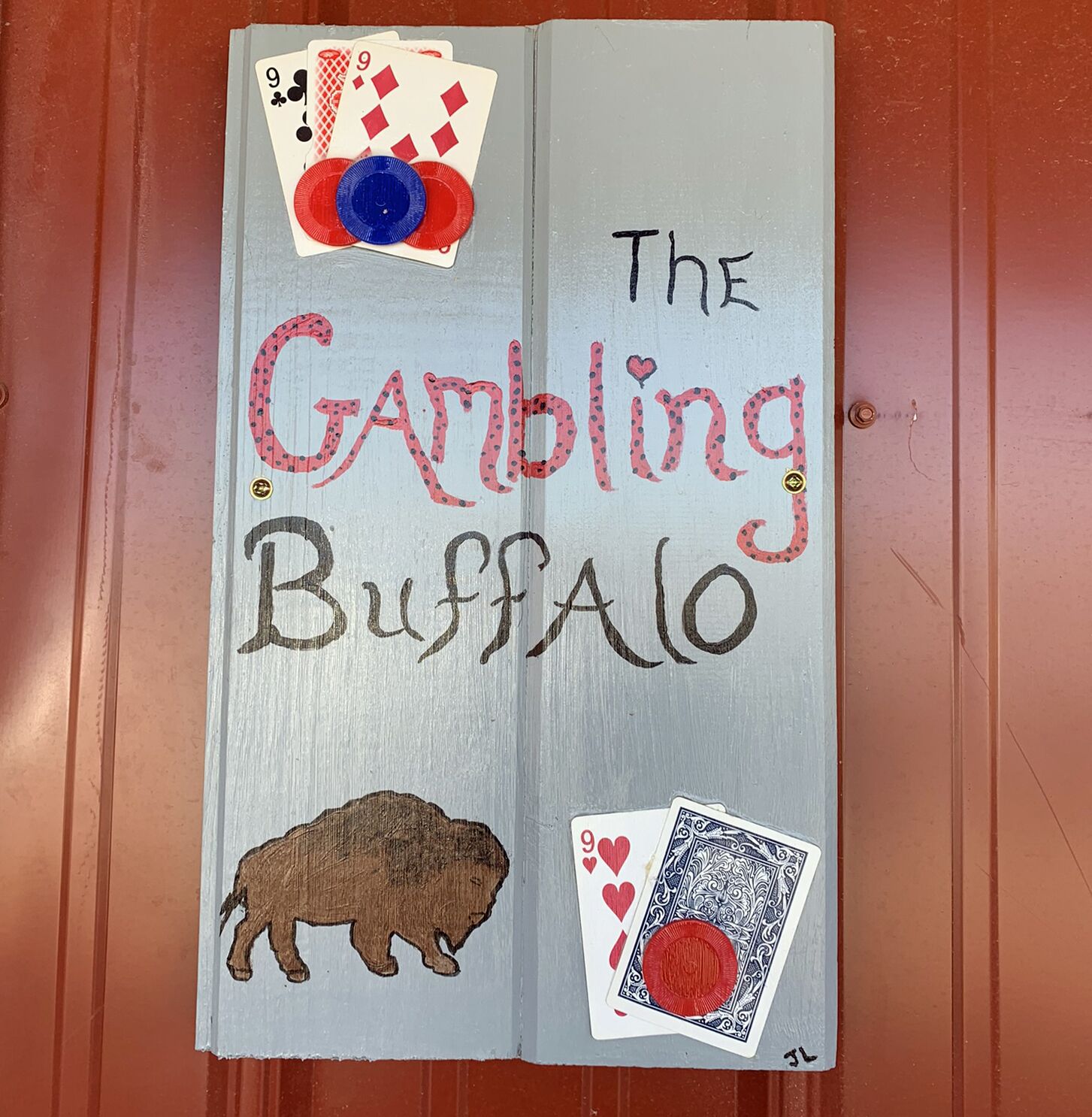 Una puerta de madera con el texto "The Gambling Buffalo" e ilustraciones de cartas de juego y un búfalo.