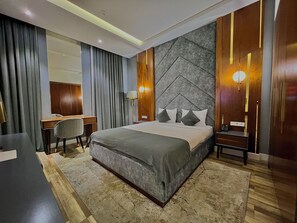 A modern hotel room with a large bed, a desk, and a chair. There are two bedside tables with lamps. - MedinaTown (Tashkent)