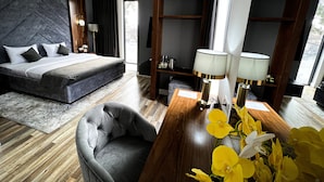 Une chambre d’hôtel moderne avec un grand lit, un bureau en bois, une chaise et une vue sur l’extérieur.